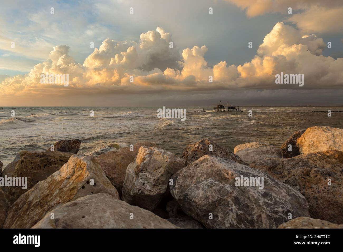 Seascape en Toscane pendant l'heure d'or après une tempête.Un Trabucco (pêche à la mashine) en arrière-plan.Nuages dans le ciel.Rochers au premier plan Banque D'Images