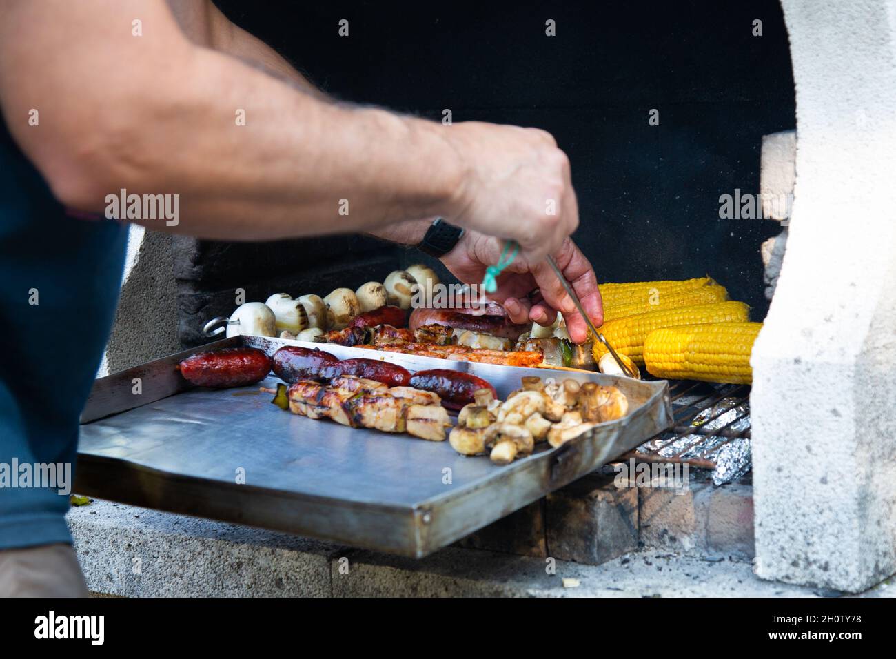 Homme méconnaissable prenant de la viande et des légumes rôtis sur le barbecue Banque D'Images