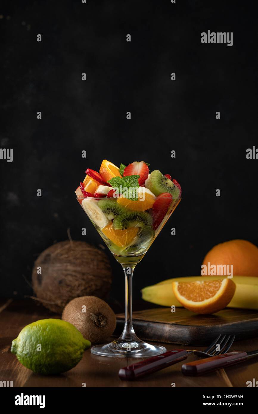 Cocktail de fruits en verre martini sur table en bois. Concept végétalien alimentaire. Banque D'Images