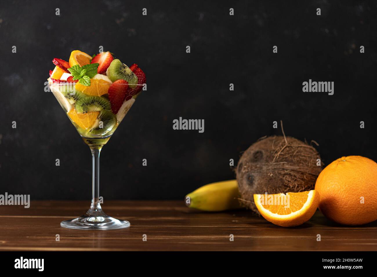 Cocktail de fruits en verre martini sur table en bois. Concept végétalien alimentaire. Banque D'Images
