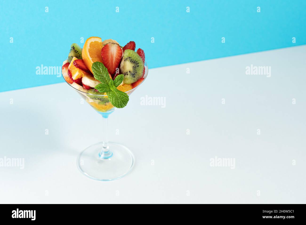 Cocktail de fruits en verre martini sur fond lumineux. Concept végétalien alimentaire minimal. Banque D'Images