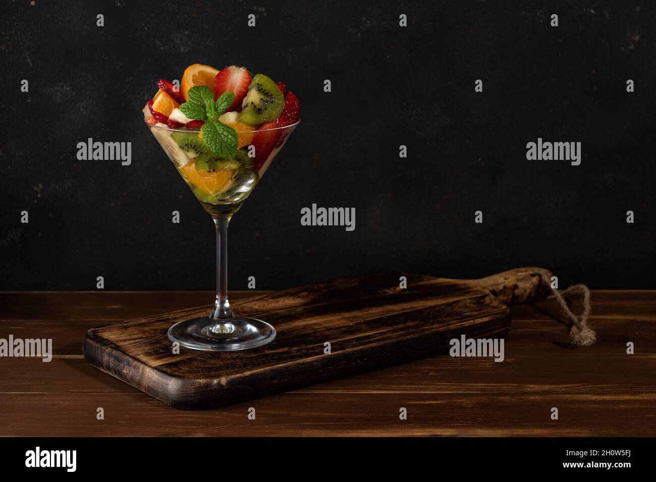 Cocktail de fruits en verre martini sur table en bois. Concept végétalien alimentaire. Banque D'Images