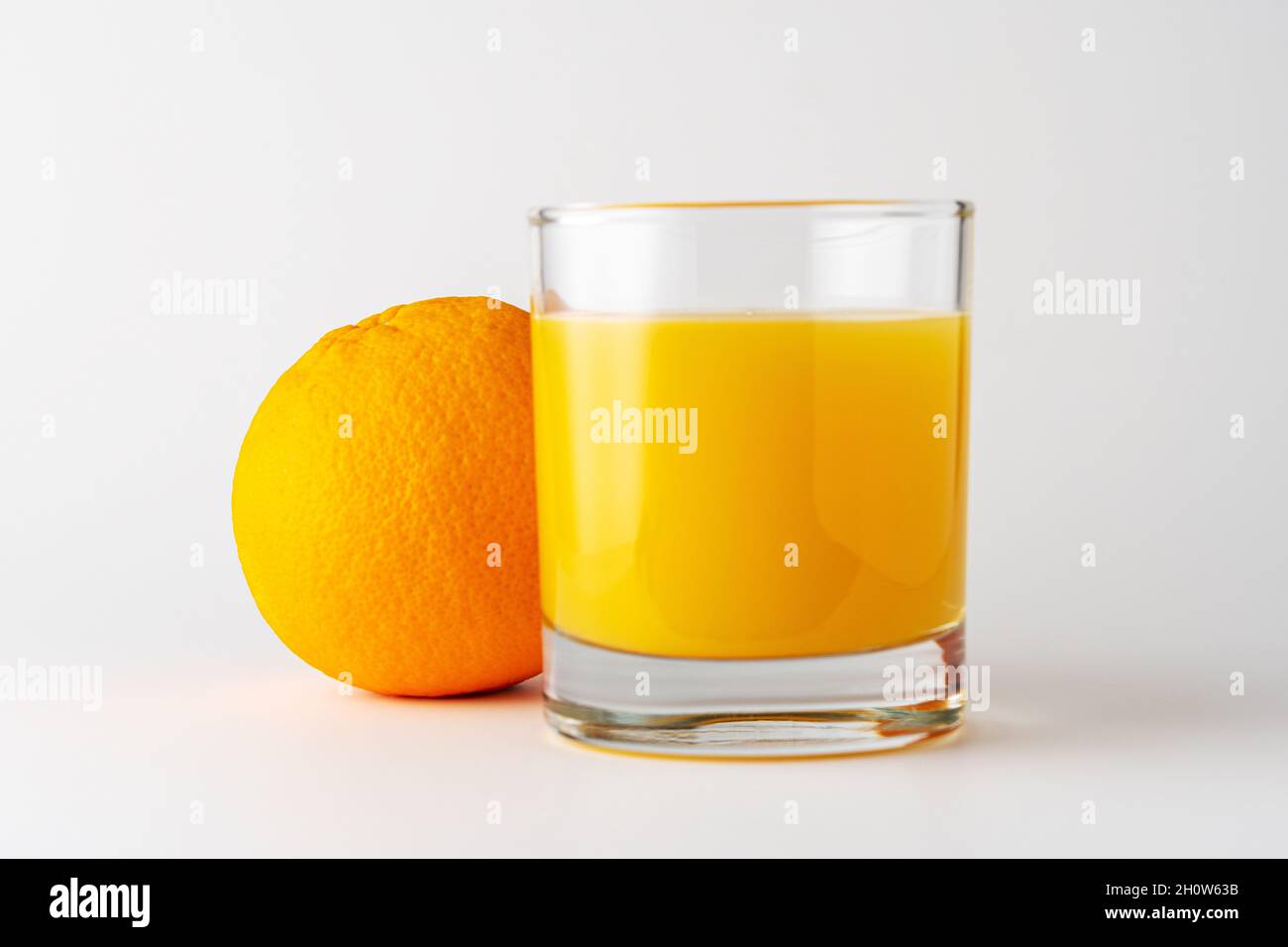 Verre de jus d'orange et de fruits d'orange sur fond blanc. Concept fruit. Banque D'Images