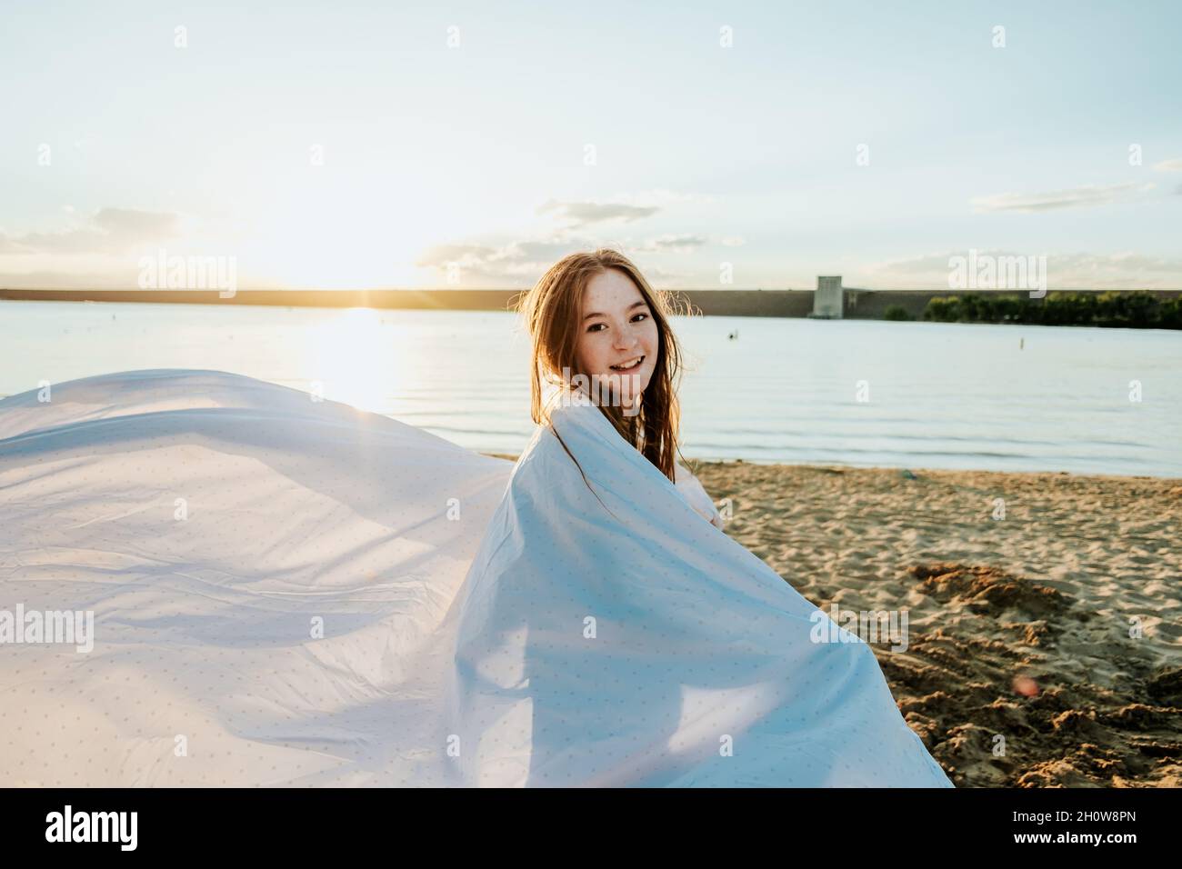 Happy Teen Girl enveloppé dans un drap à la plage Banque D'Images