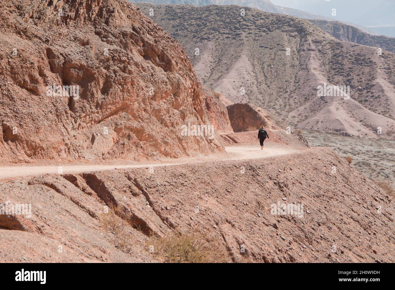 Une femme aventureuse qui fait de la randonnée sur la route sinueuse sur la montagne de sable rocheux Banque D'Images