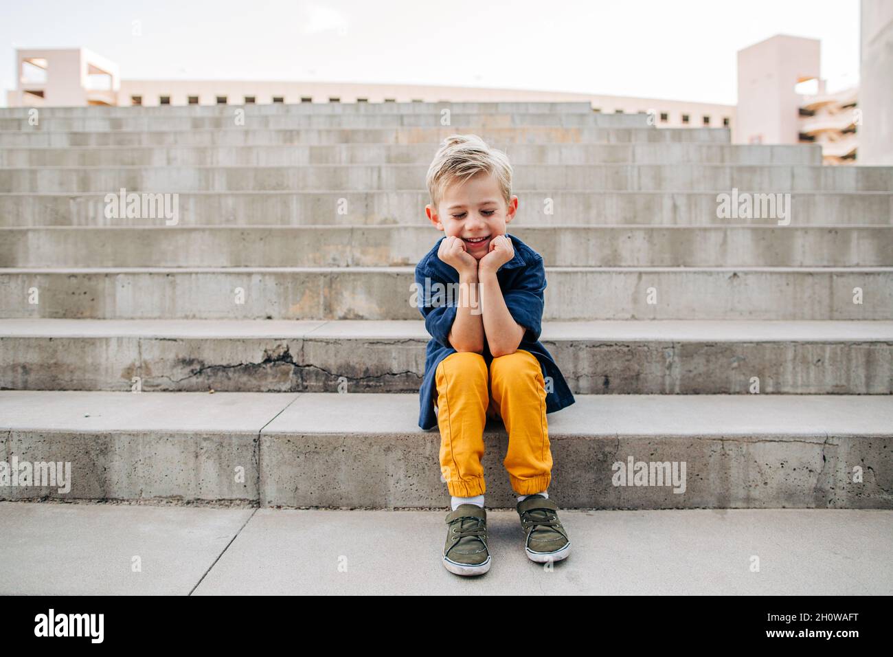 Portrait d'un jeune garçon en train de rire sur des marches en béton dans le centre-ville de Phoenix Banque D'Images