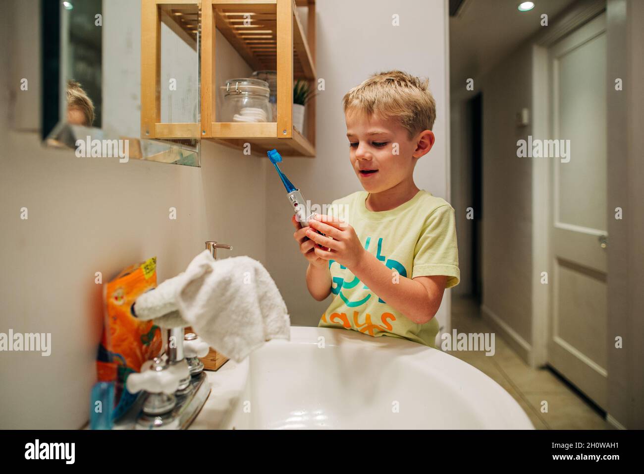 Un jeune garçon se brosse les dents avec une brosse à dents électrique Banque D'Images