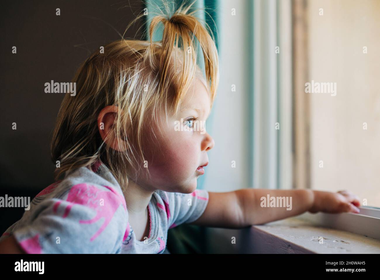 La petite fille à yeux bleus donne sur la fenêtre avant de la maison de Phoenix Banque D'Images