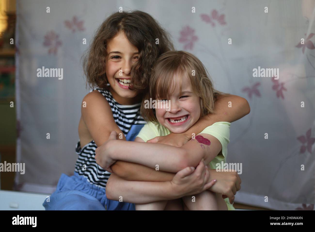 Les filles aux cheveux foncés et aux cheveux blonds s'embrassent. Banque D'Images