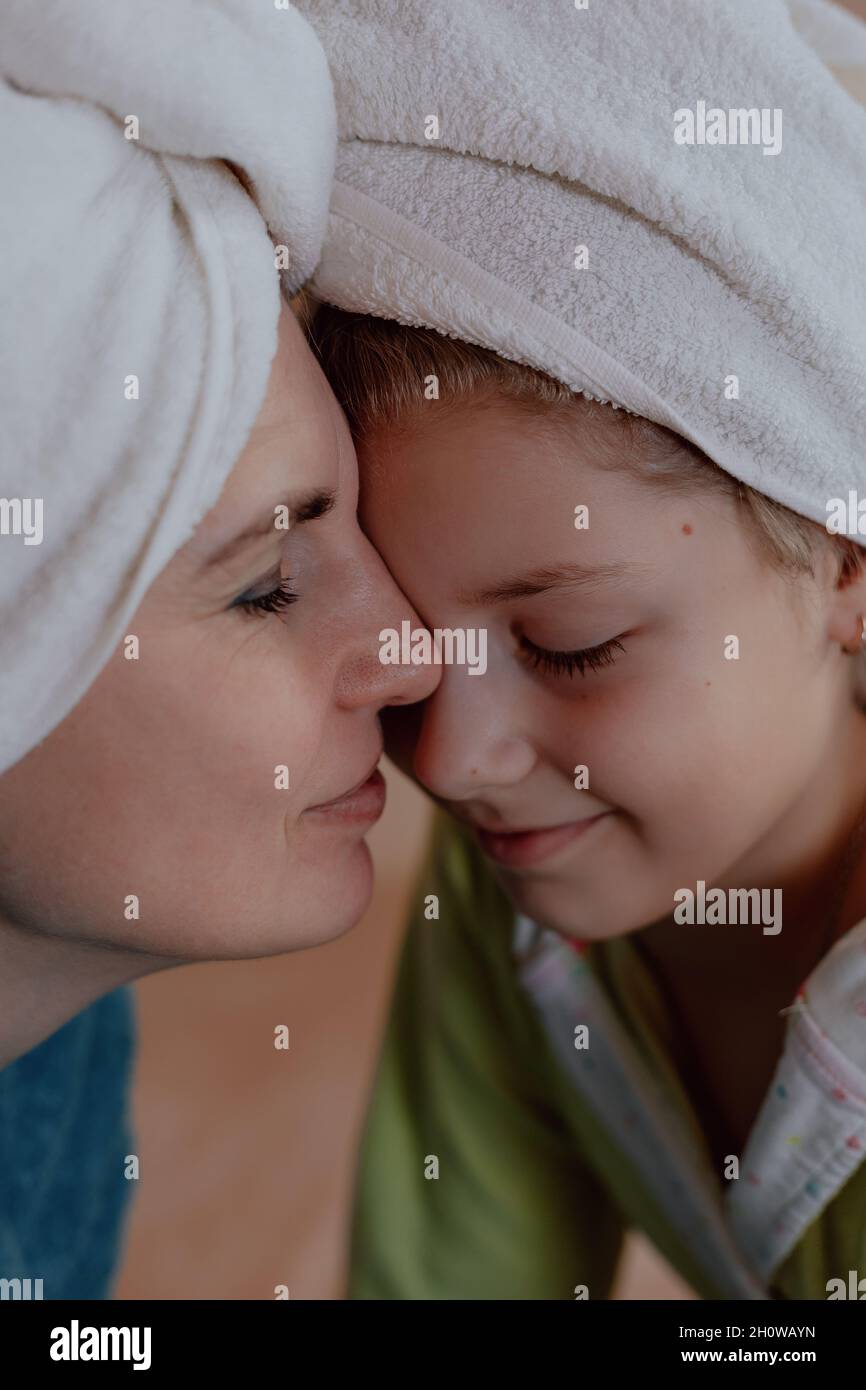 Une jeune femme du caucase avec sa fille sur un lit à la maison le matin, portant une serviette Banque D'Images