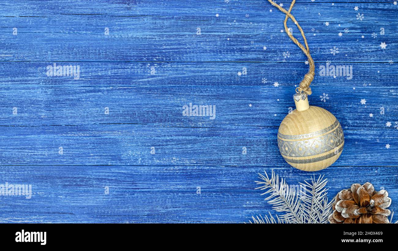 boule de noël en bois et branche de sapin avec cône de pin sur planches en bois peintes en bleu. carte de vœux des vacances d'hiver. pose à plat. espace de copie. Banque D'Images