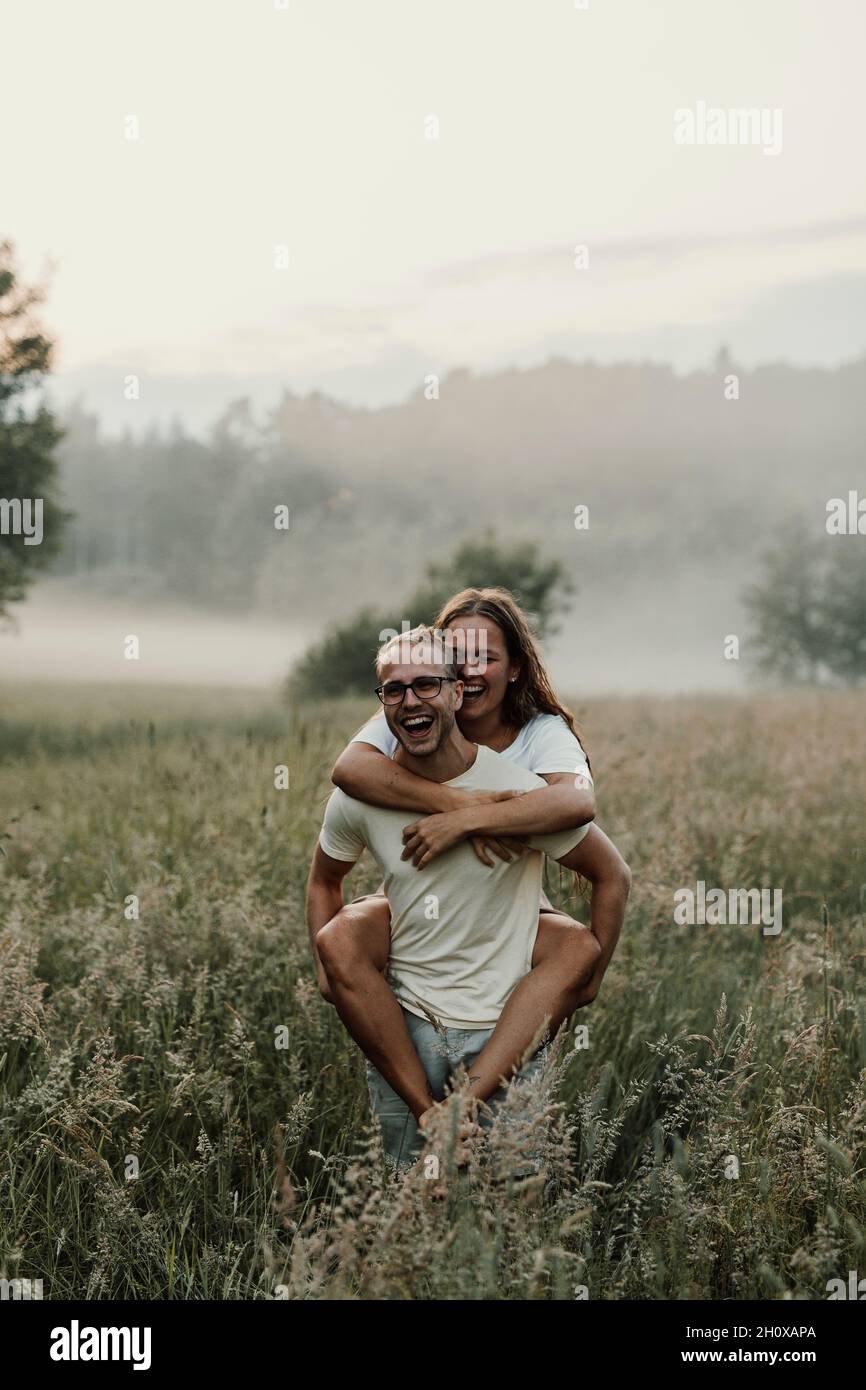 Man giving girlfriend piggyback ride Banque D'Images