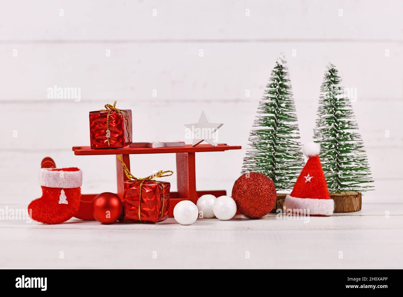 Organisation de Noël avec toboggan rouge, arbres, boîtes-cadeaux, chaussettes et chapeau de père noël Banque D'Images