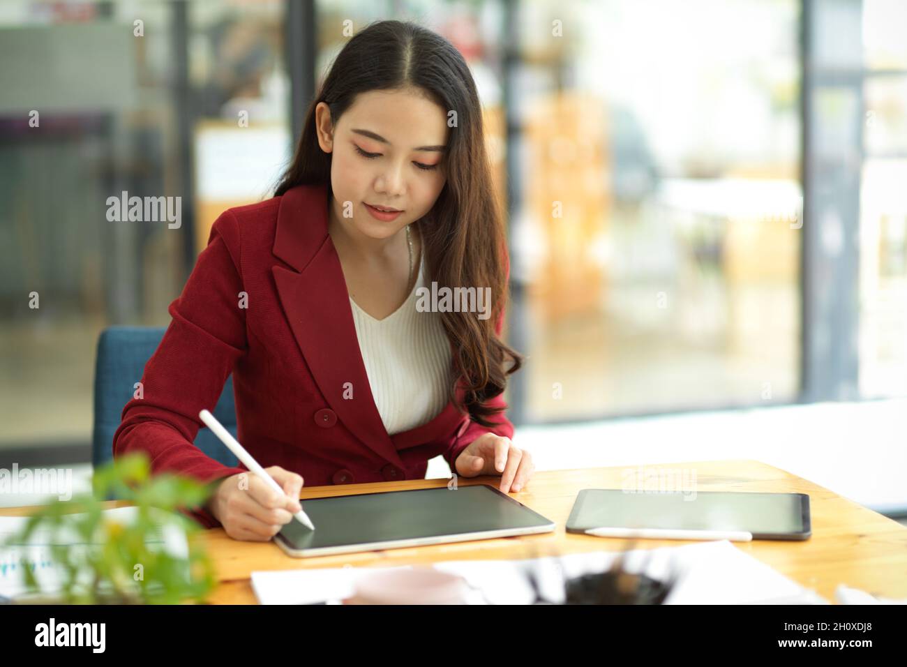 Femme d'affaires du millénaire utilisant un stylet pour dessiner des cartes d'esprit d'entreprise sur une tablette numérique portable à son bureau Banque D'Images