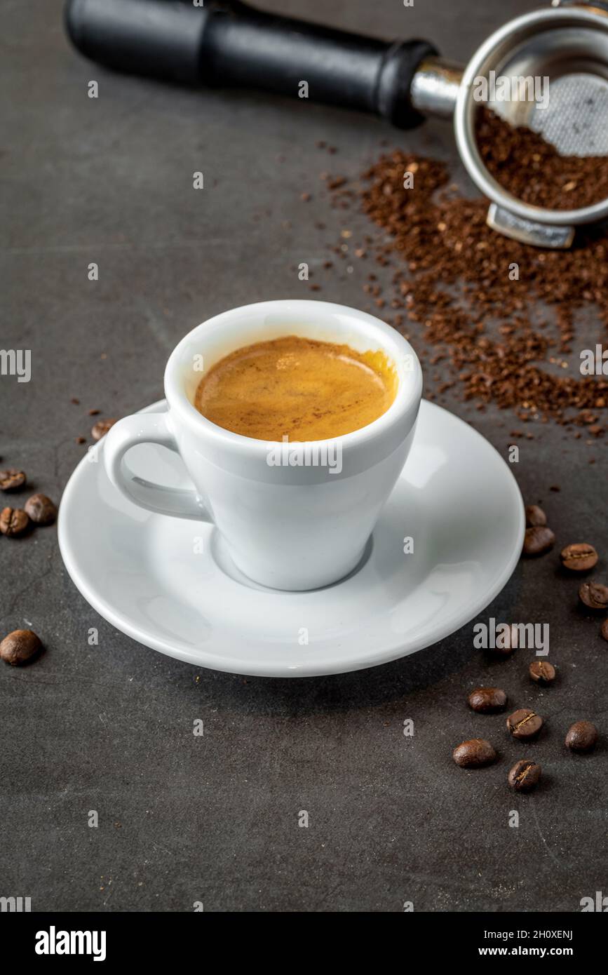 Café expresso frais avec grains de café sur fond sombre Banque D'Images
