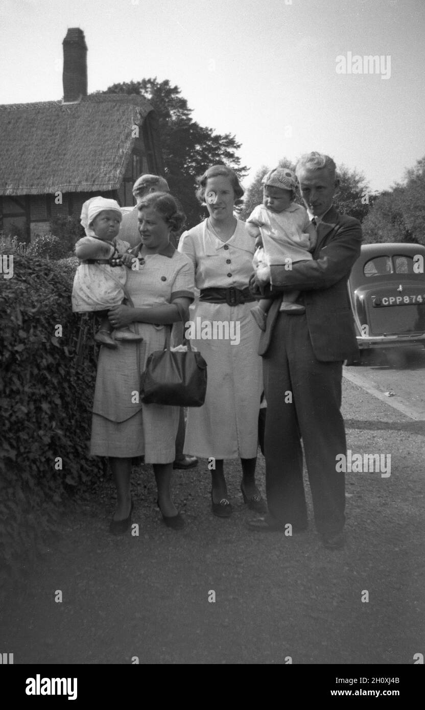 Fin des années 1940, historique, une famille avec des nourrissons debout pour une photo à l'extérieur de la maison, Stratford-upon-Avon, Angleterre, Royaume-Uni. Banque D'Images
