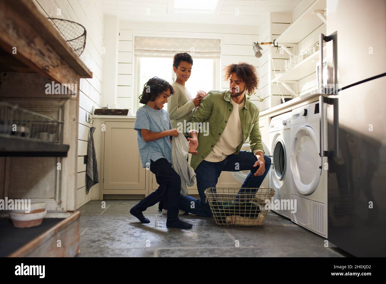 Le père et les fils chargent la machine à laver dans la cuisine Banque D'Images