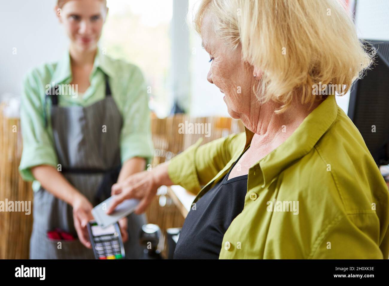 Client disposant d'un smartphone pendant le paiement mobile à la caisse NFC dans le centre de jardin Banque D'Images
