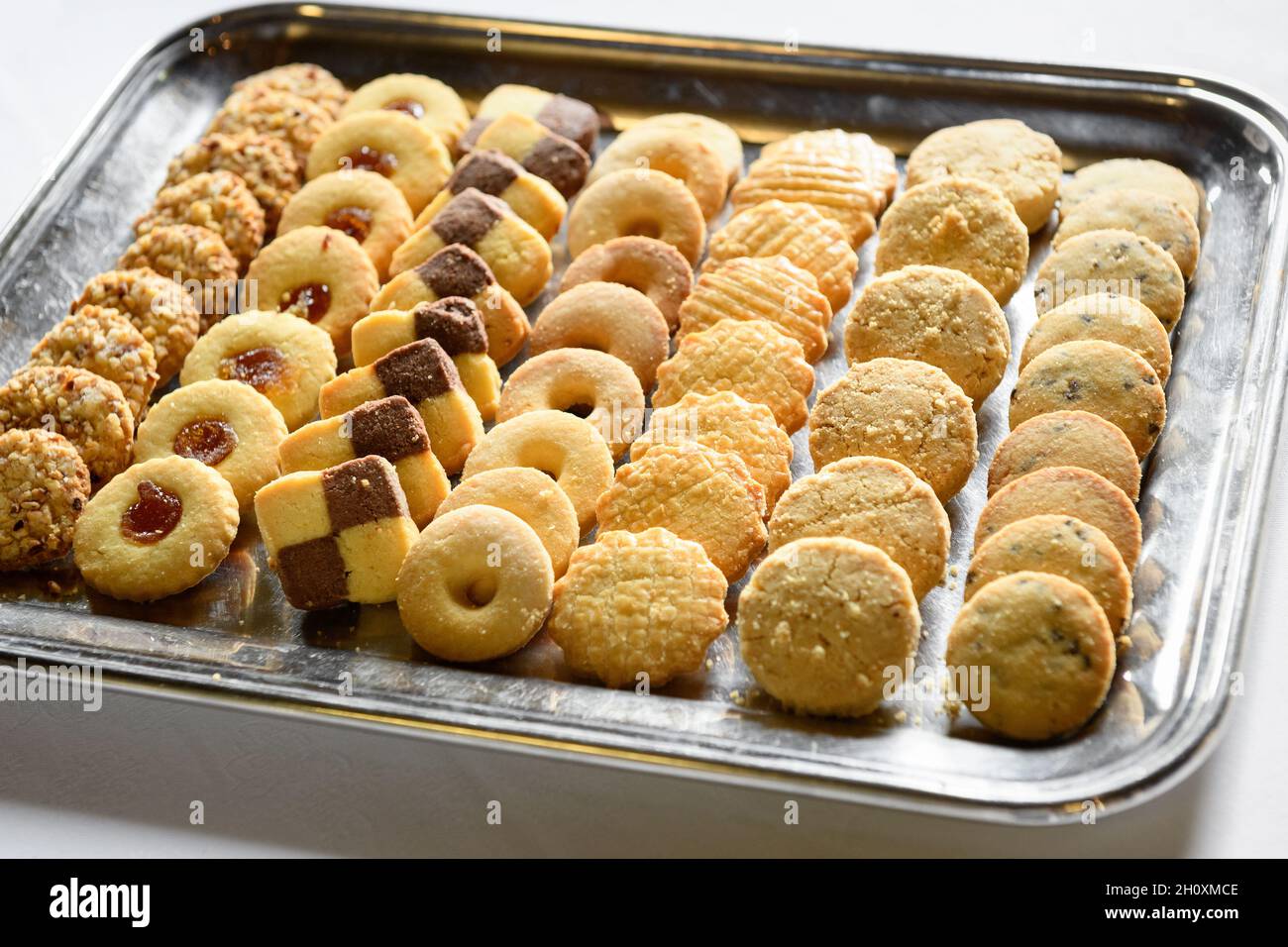 De délicieux biscuits artisanaux sucrés placés sur un plateau argenté sur une table blanche en journée Banque D'Images