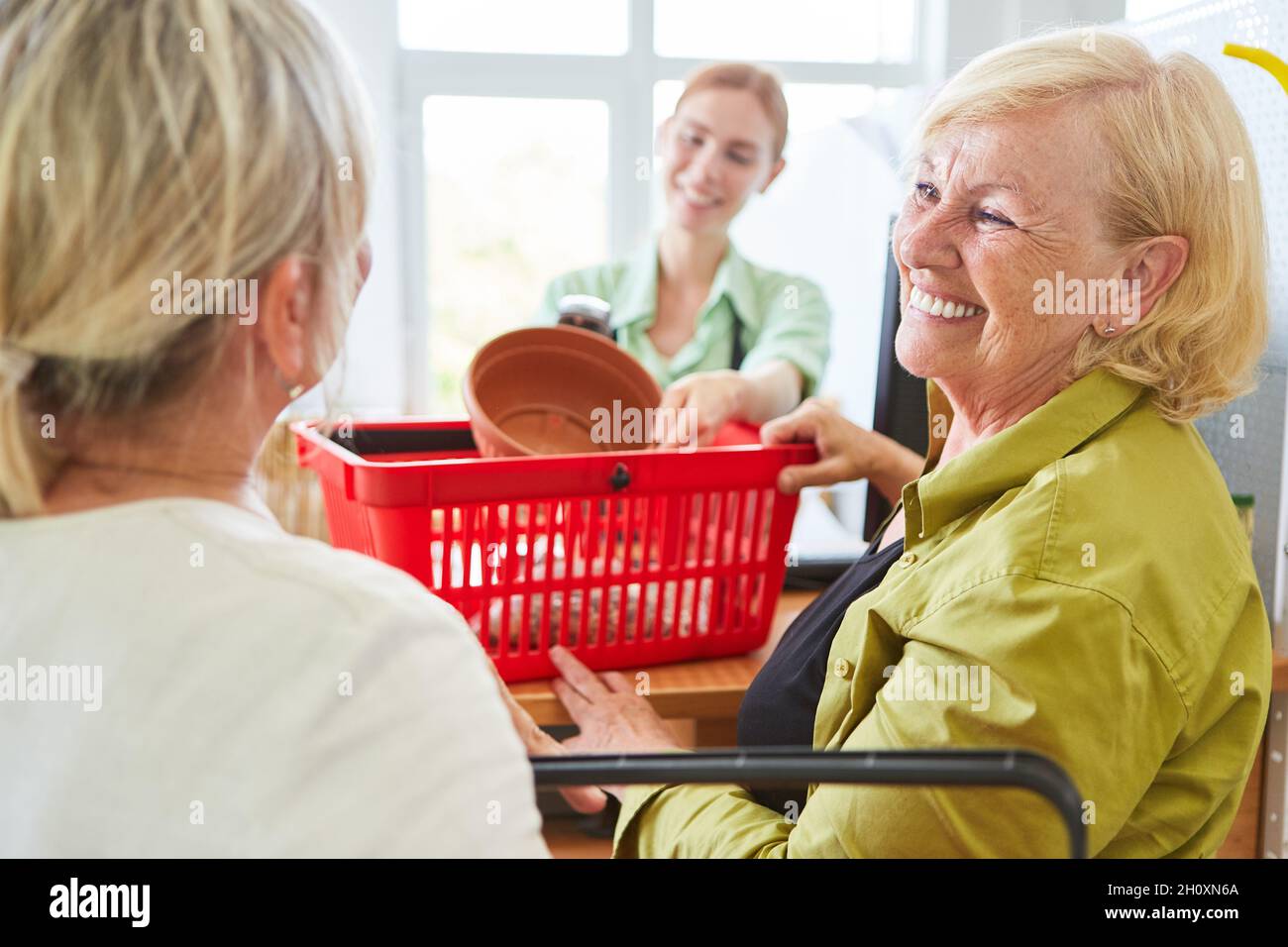 Client souriant lors du paiement à la caisse du centre de jardin ou de la quincaillerie Banque D'Images