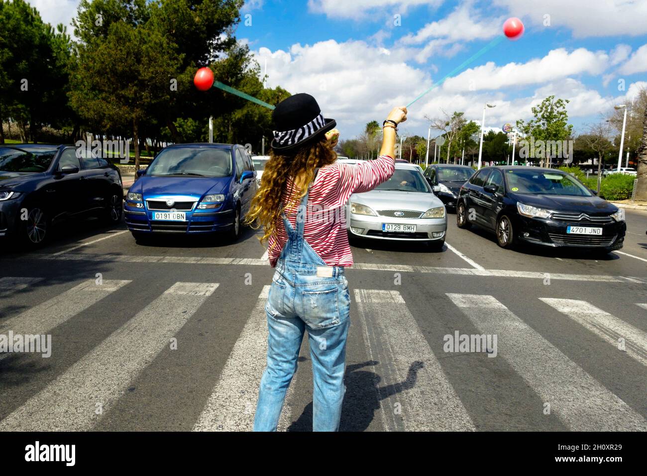 Femme interprète de rue avec des balles sur un passage à niveau pour recueillir de l'argent des automobilistes Valence Espagne Banque D'Images