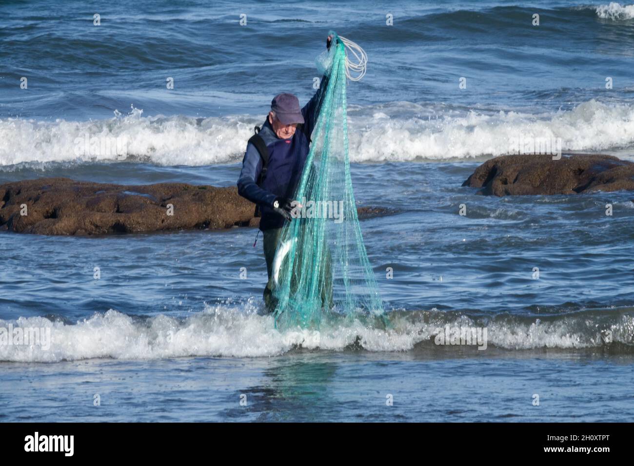 Vieil homme senior pêcheur filet de capture de poisson seul Espagne mer Banque D'Images