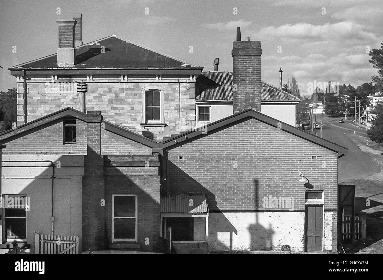 Construite entre 1868 et 1913, la gare du Mont Victoria comprend plusieurs bâtiments, dont le bâtiment d'origine de la gare sur toit en pierre et ardoise sur la plate-forme 2, (LHS) un bâtiment de la gare de la Nouvelle-Galles du Sud de deuxième classe de type 3.Les bâtiments en briques et en carreaux contigus au bâtiment principal en pierre ont été construits vers 1913.Cette image a été prise quelque temps en 1977-78 et montre la collection de bâtiments de l'extrémité ouest et la route menant au village de Mt Victoria Banque D'Images