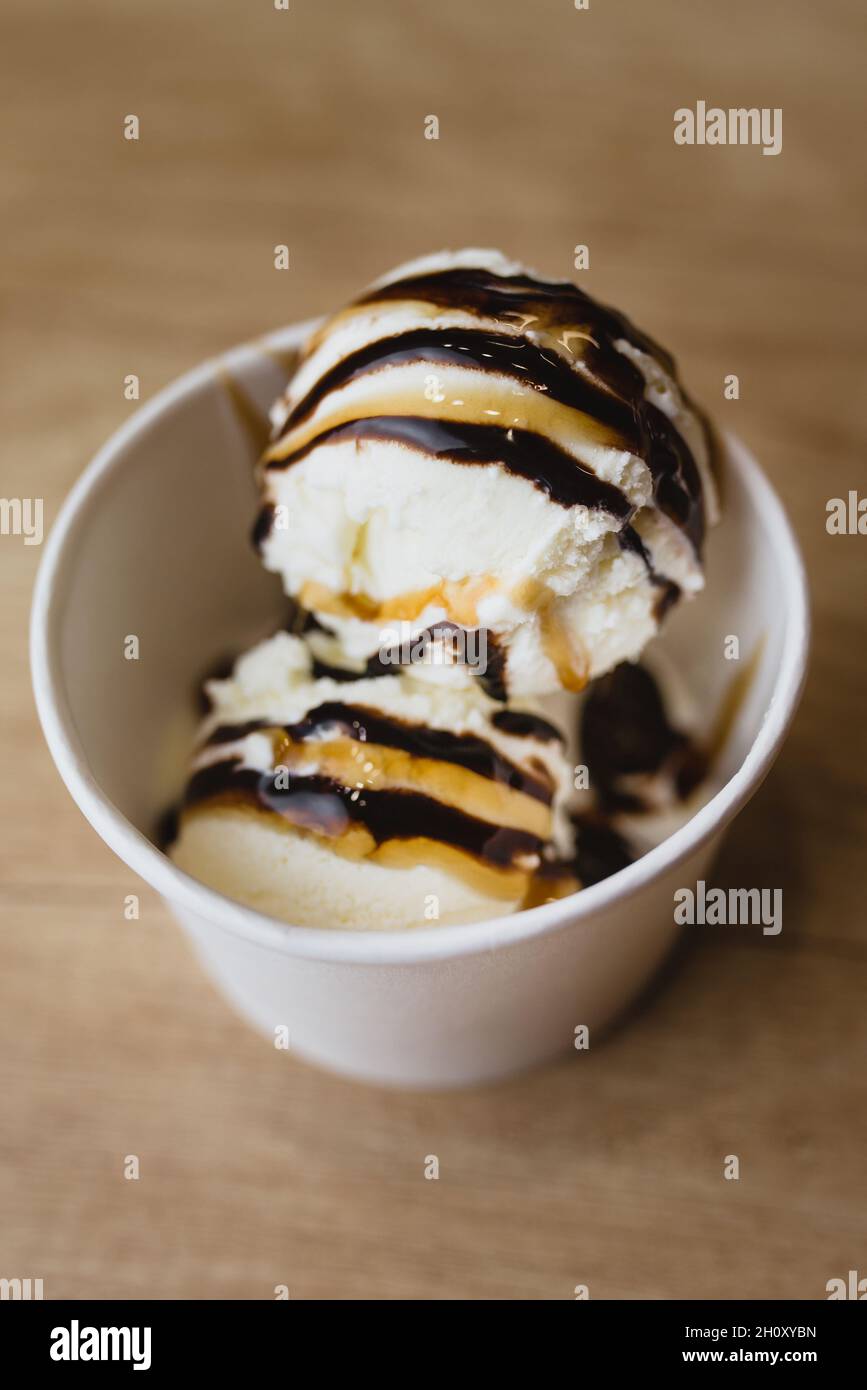 Boules de crème glacée crémeuse dans une tasse en carton avec garniture au caramel au chocolat Banque D'Images