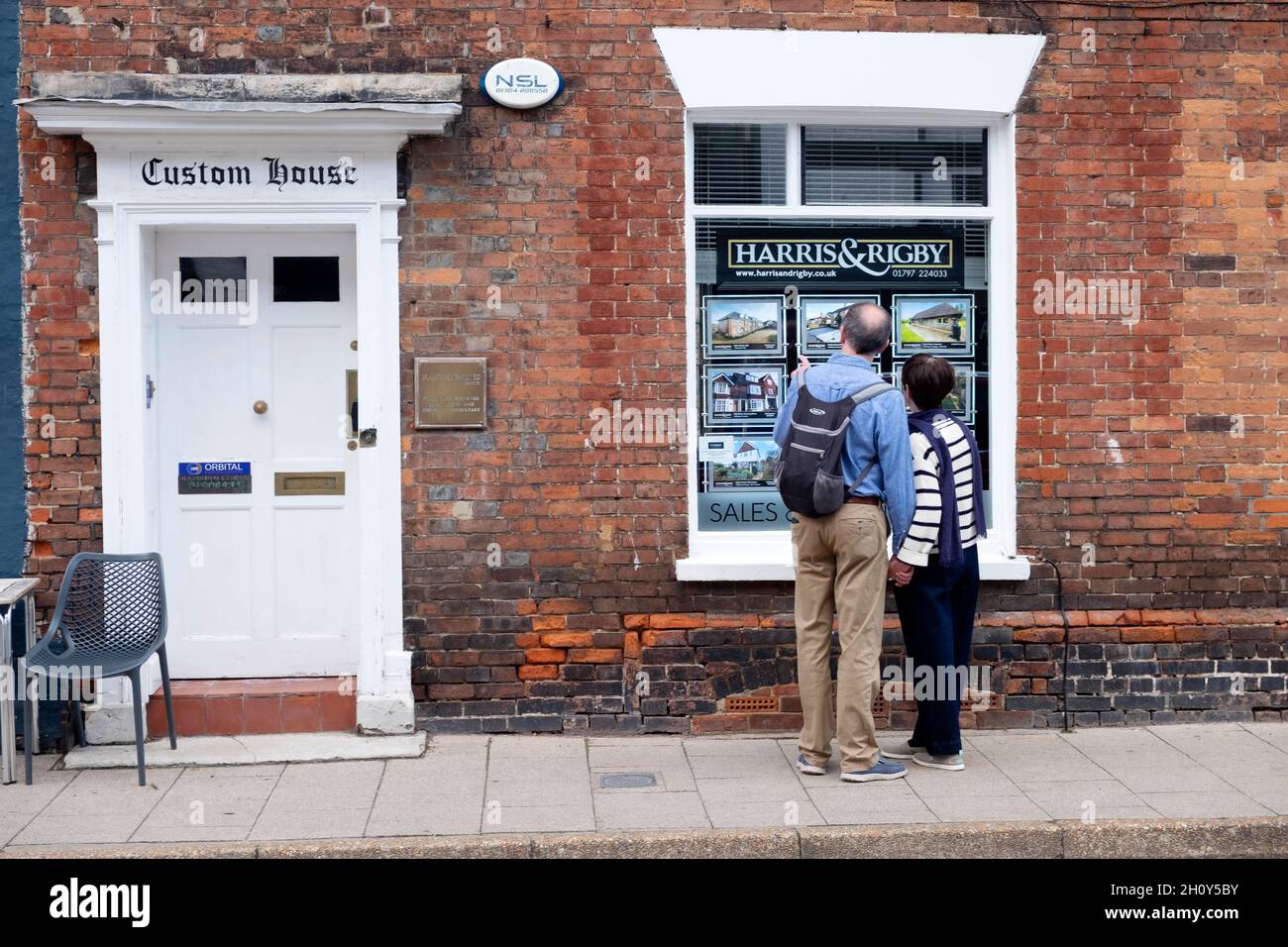 Couple personnes regardant dans la fenêtre de l'agent immobilier à des maisons à vendre louer immobilier de marché à Rye East Sussex Angleterre Grande-Bretagne Royaume-Uni KATHY DEWITT Banque D'Images