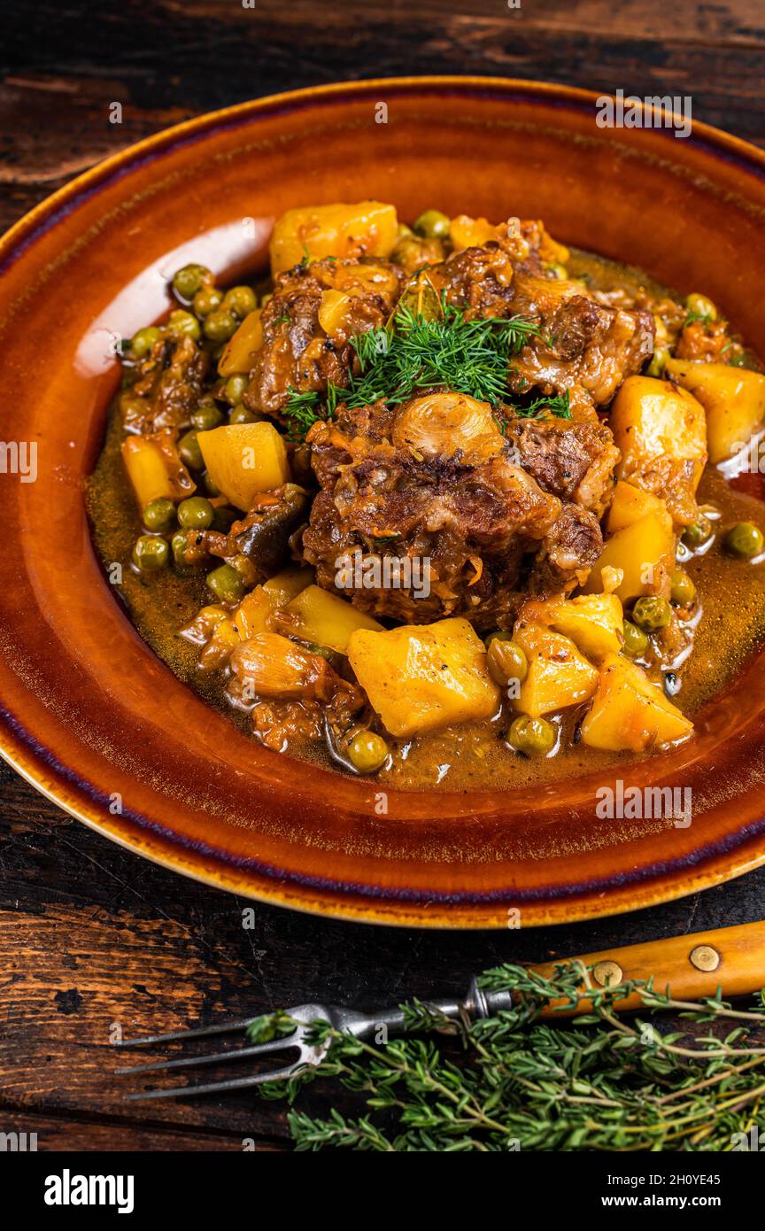 Ragoût de bœuf d'agneau avec légumes dans un plat rustique. Arrière-plan en bois sombre. Vue de dessus Banque D'Images