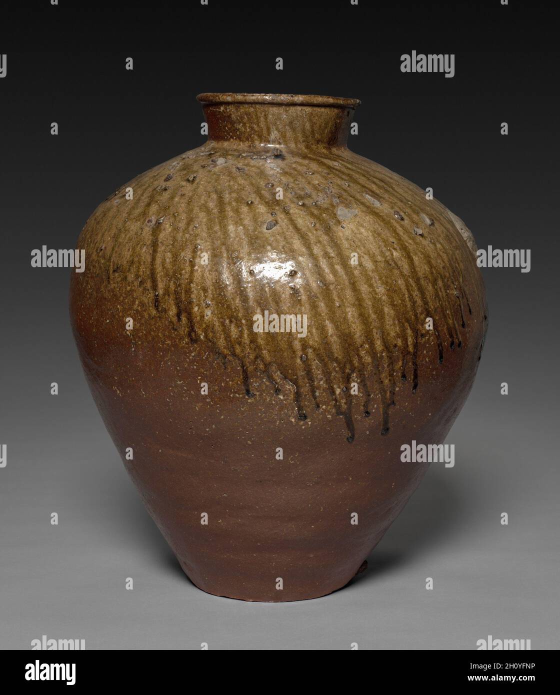 Bol de rangement, 1400 s.Japon, période de Muromachi (1392-1573).Grès avec glaçure de frêne naturelle (vaisselle Echizen); diamètre: 47.5 cm (18 11/16 in.); hors tout: 57.5 cm (22 5/8 in.).Situé dans la préfecture d'Fukui au nord-est de Kyoto, les fours Echizen produisaient des céramiques avec une peau rouge-violacé et un feldspath blanc caractéristique de l'argile locale utilisée dans cette pièce.Vers 1700, la chaude teinte des produits Echizen a gagné en popularité dans la pratique du thé, en particulier lorsque les navires ont exposé la surface robuste évidente ici en combinaison avec les gouttes dynamiques de glaçure brillante. Banque D'Images