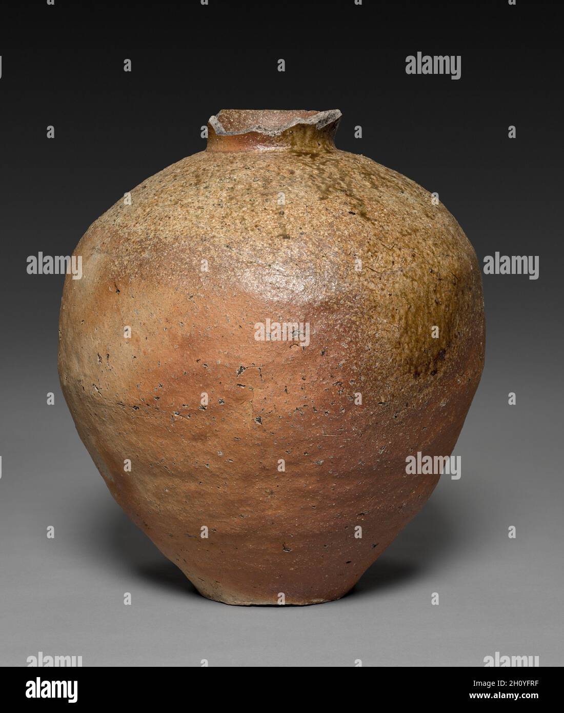 Pot de rangement (Tsupo), 1400 s.Japon, période de Muromachi (1392-1573).Grès avec glaçure de frêne naturelle (Shigaraki ware); diamètre: 47.5 cm (18 11/16 in.); hors tout: 53 cm (20 7/8 in.).Ce pot en argile bulbeux, avec sa surface orange-marron, sèche et expansive, des points blancs de pierre feldspathe, et des marques de crasure épidery incarnent un type de matériel médiéval de Shigaraki.Cette région à l'est de Kyoto et au nord de l'ancien centre culturel et religieux de Nara a longtemps été connue comme une source d'argile supérieure.Les bocaux de stockage Shigaraki ont été conçus pour offrir robustesse et durabilité.Le vaisseau est légèrement lopsid Banque D'Images
