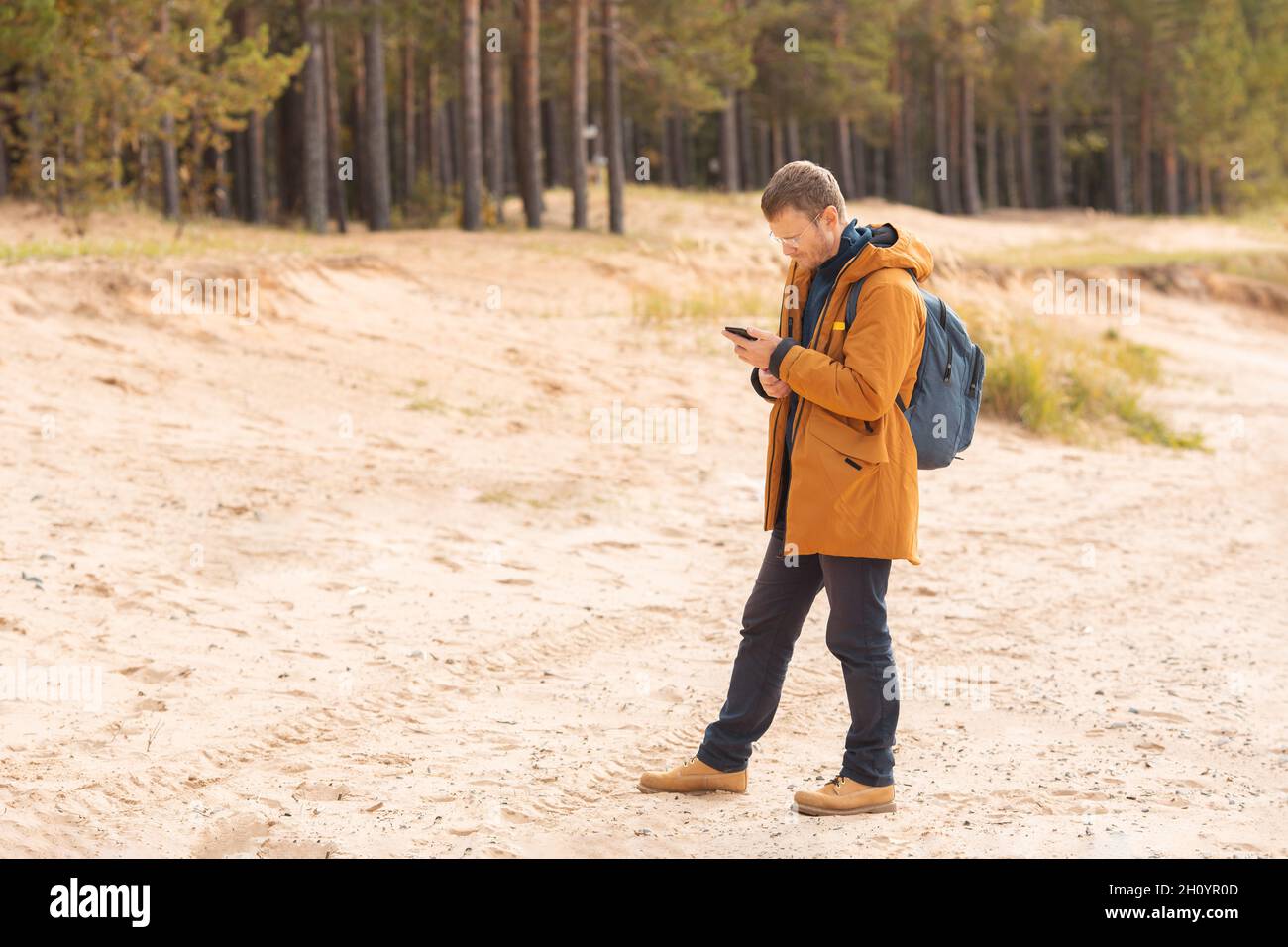 Homme caucasien avec un smartphone dans sa main debout sur la plage.Un homme cherche son emplacement sur le sol - image Banque D'Images