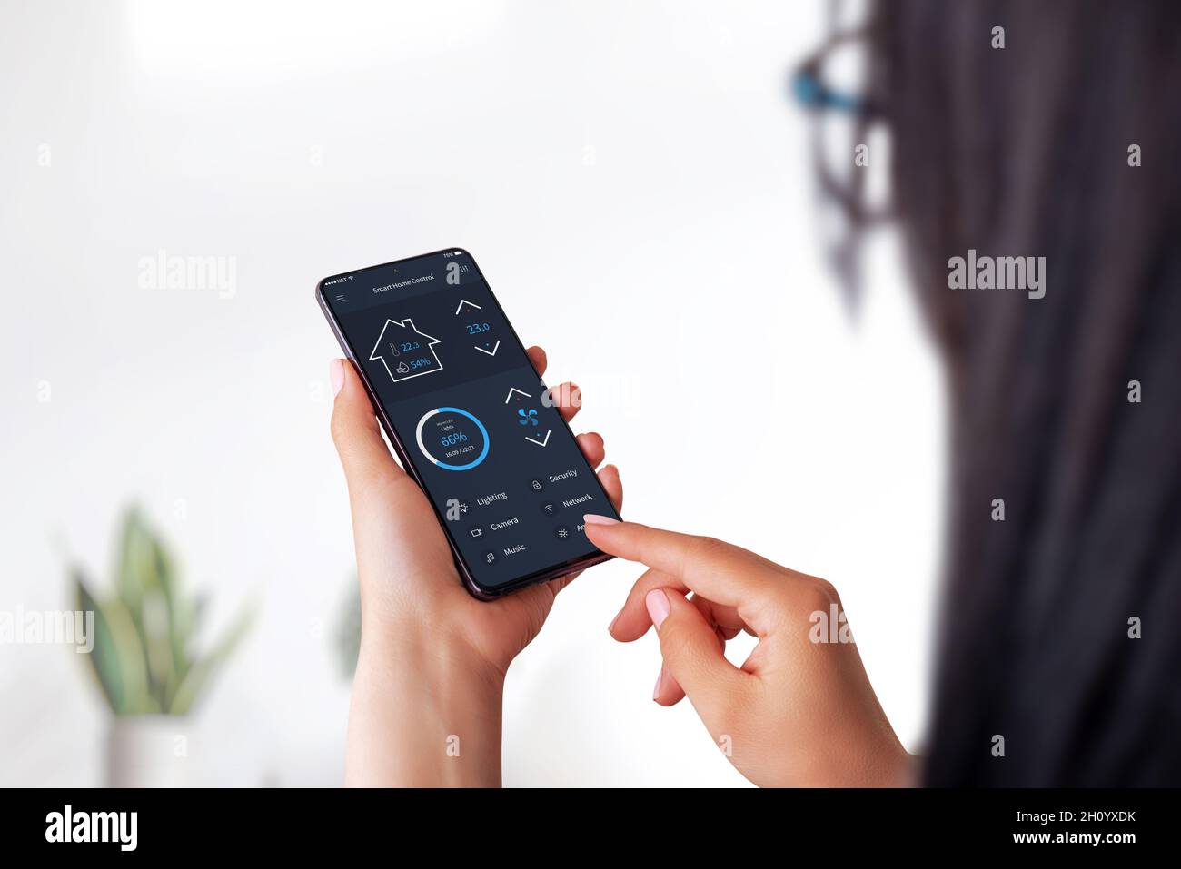 Concept de l'application Smart Home sur smartphone entre les mains des femmes.Intérieur de la maison en arrière-plan Banque D'Images