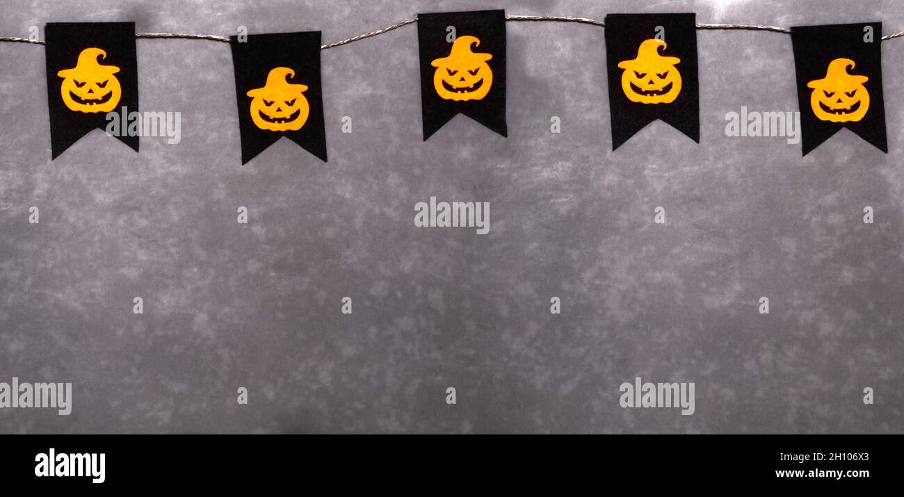 Guirlande pour Halloween.Citrouilles orange aux visages effrayants sur fond noir.Décoration de fête.Bannière.Copier l'espace. Banque D'Images