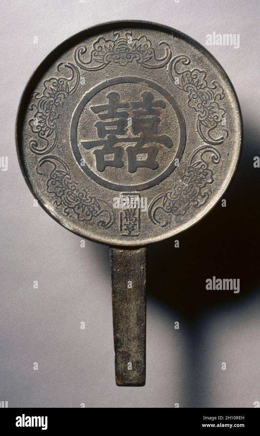 Miroir avec poignée, décoré de « Double bonheur » et de cinq bates, c.1800. Atelier de Tang Wanheng (chinois, actif c.1800).Laiton; diamètre: 16.5 cm (6 1/2 in.); hors tout: 0.6 cm (1/4 in.); rebord: 0.6 cm (1/4 in.). Banque D'Images