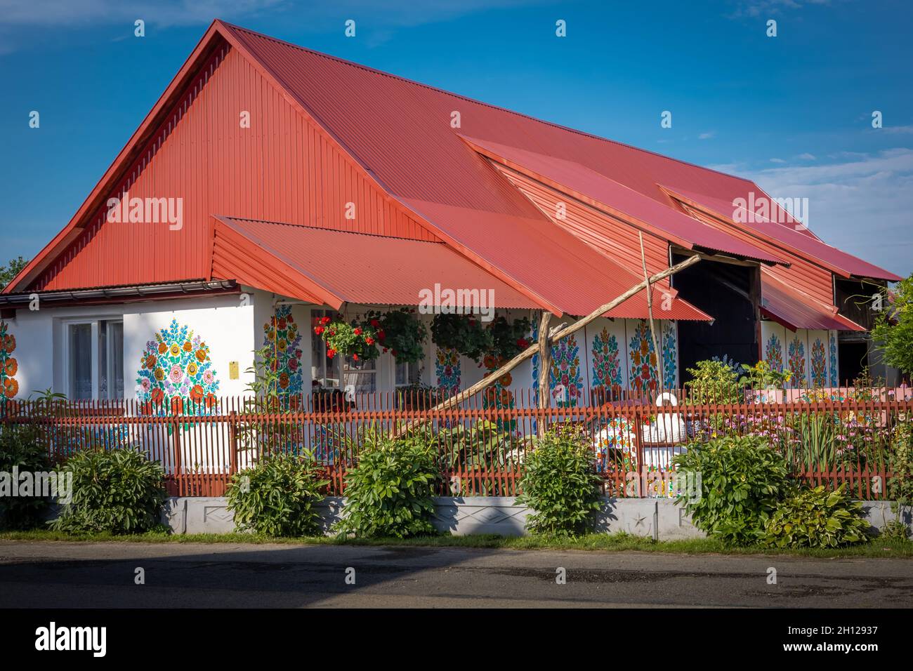 Zalipie, Pologne - 1 août 2021 : une maison avec un toit orange et des murs peints dans un motif floral coloré.Jour ensoleillé, ciel bleu. Banque D'Images