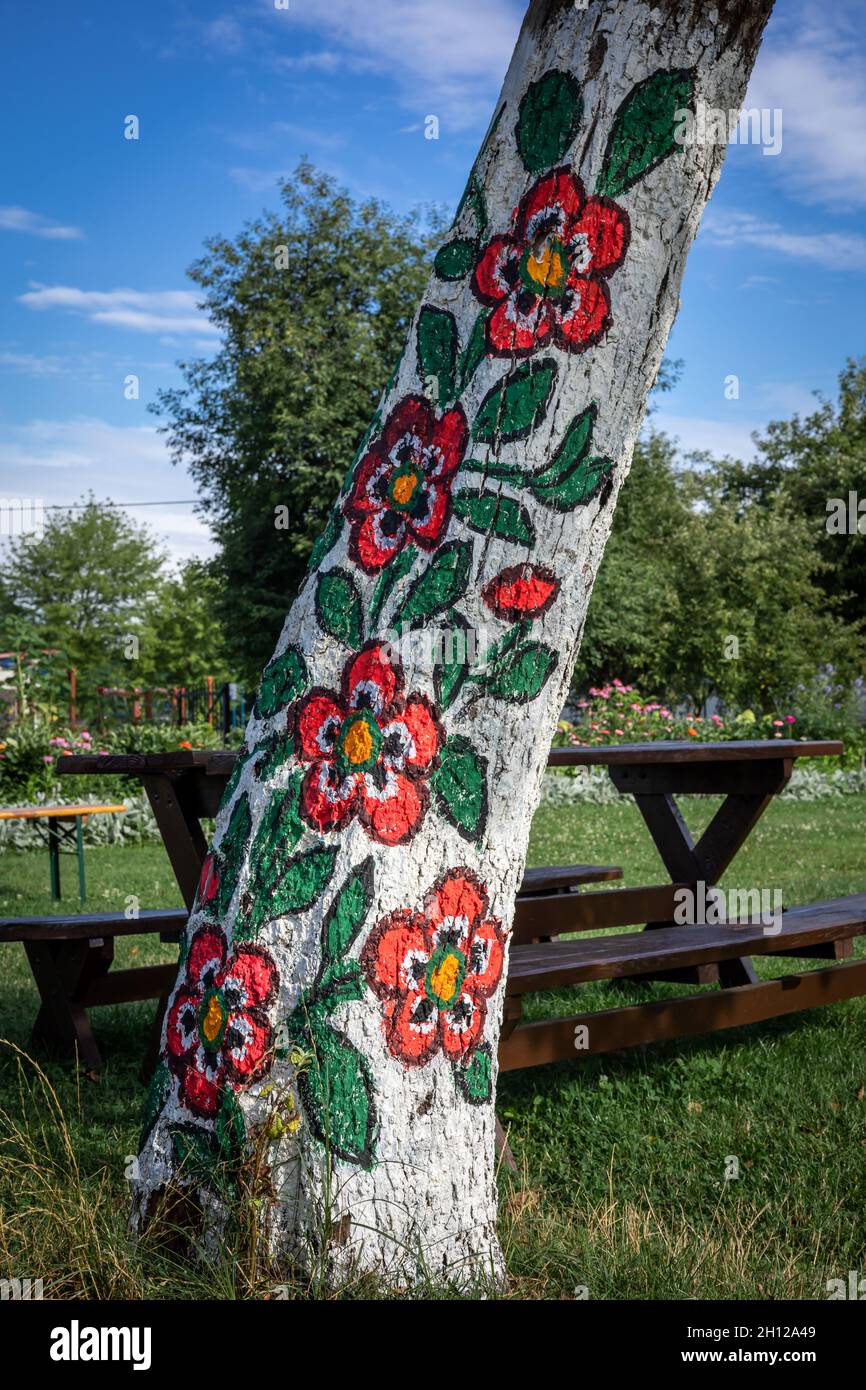 Zalipie, Pologne - 1 août 2021 : tronc d'arbre peint en motif floral coloré.Ensoleillé, jour d'été. Banque D'Images