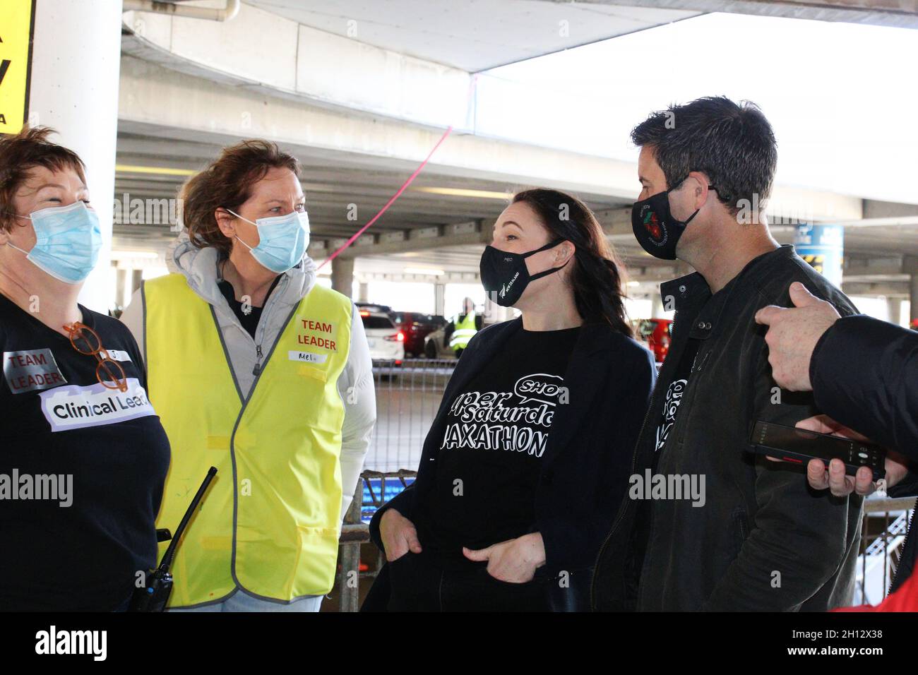 Wellington, Nouvelle-Zélande.16 octobre 2021.Le Premier ministre néo-zélandais Jacinda Ardern, deuxième de droite, avec son partenaire Clarke Gayford (à l'extrême droite) rira avec des vaccinateurs lors d'un trajet à travers le centre de vaccination Covid-19 installé au stade Sky pour le « Super Saturday Vaxathon » .Crédit : Lynn grief/Alamy Live News Banque D'Images