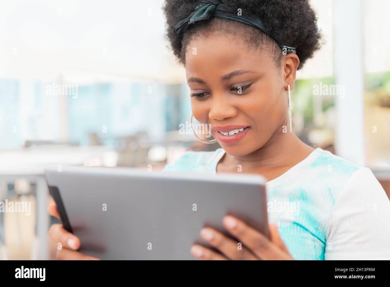 Une femme adulte gaie assise dehors en utilisant et regardant sa tablette numérique Banque D'Images