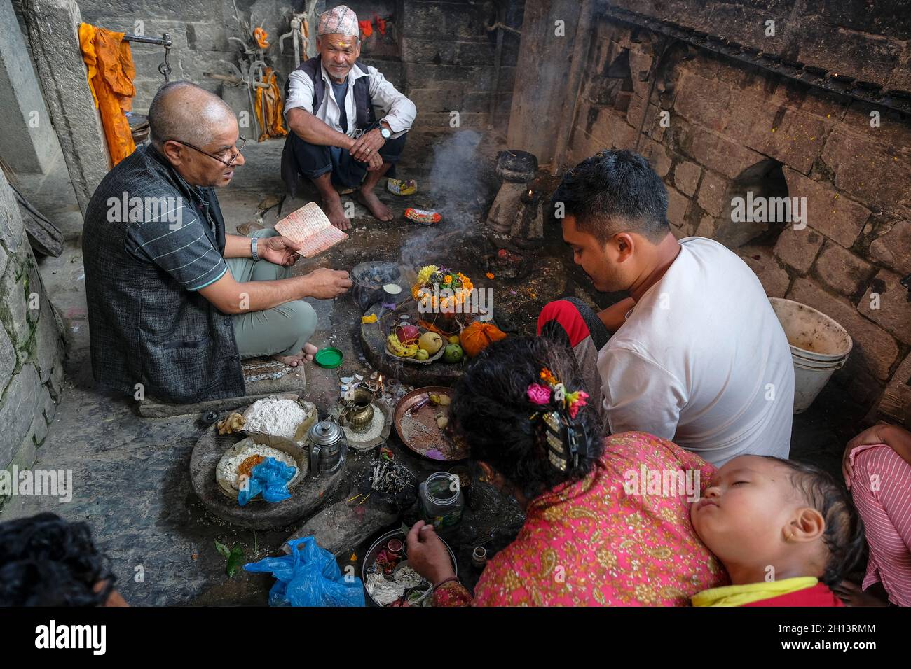 Bhaktapur, Népal - octobre 2021: Une famille faisant une offrande au ghat Hanuman à Bhaktapur le 10 octobre 2021 dans la vallée de Katmandou, Népal. Banque D'Images