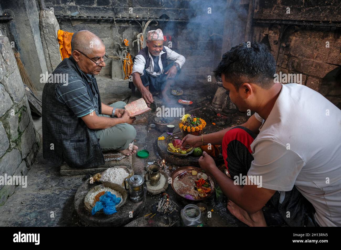 Bhaktapur, Népal - octobre 2021: Une famille faisant une offrande au ghat Hanuman à Bhaktapur le 10 octobre 2021 dans la vallée de Katmandou, Népal. Banque D'Images