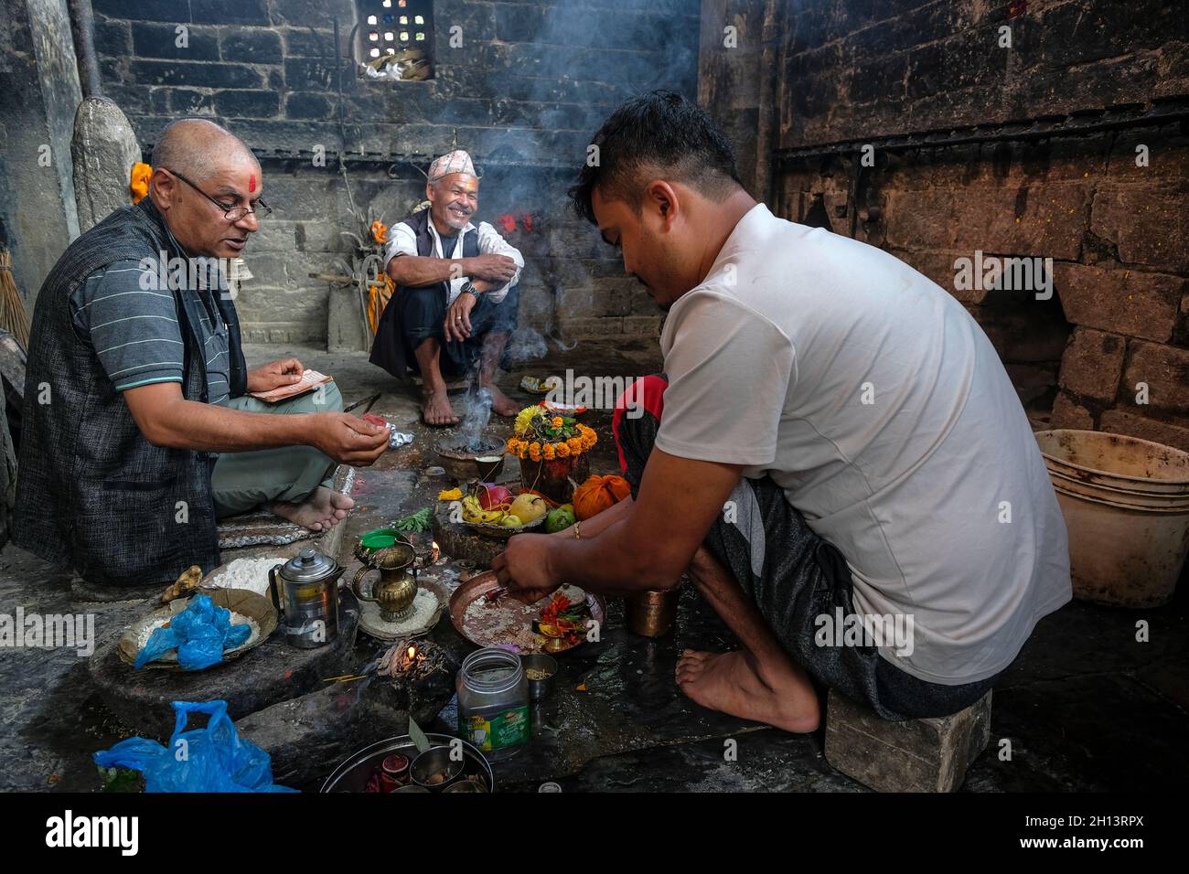Bhaktapur, Népal - octobre 2021: Une famille faisant une offrande au ghat Hanuman à Bhaktapur le 10 octobre 2021 dans la vallée de Katmandou, Népal. Banque D'Images