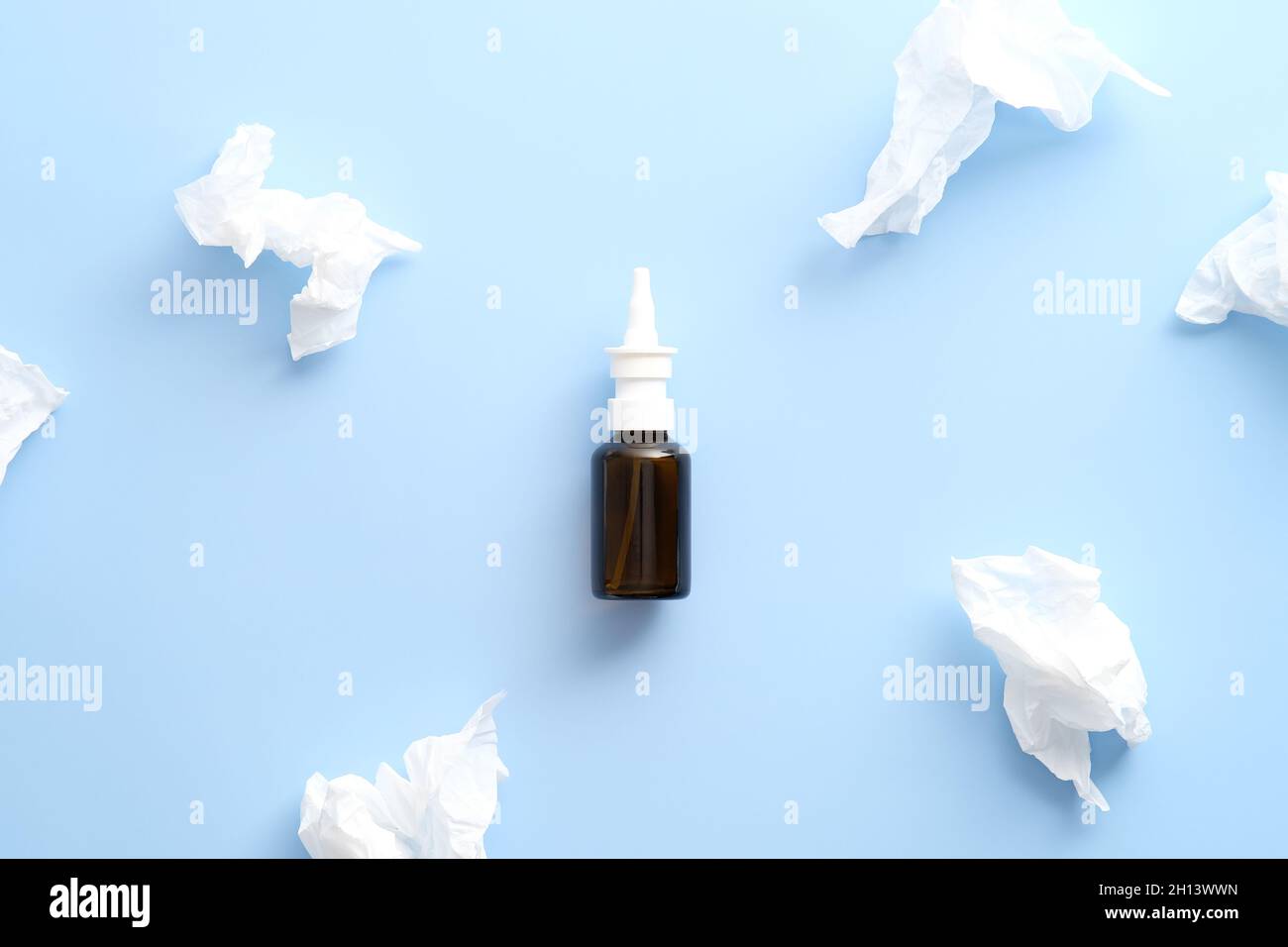 Vaporisateur hydratant nasal et mouchoirs en papier sur fond bleu pastel.Flat lay, vue de dessus.Grippe, concept de traitement du rhume. Banque D'Images