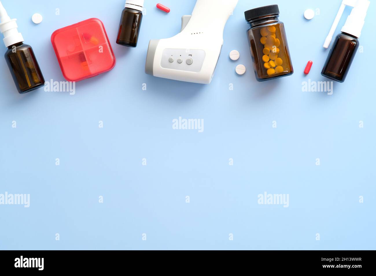 Traitements de la grippe.Sprays nasaux, pilules pour traiter les rhumes, thermomètre numérique sur fond bleu pastel.Flat lay, vue de dessus, espace de copie. Banque D'Images