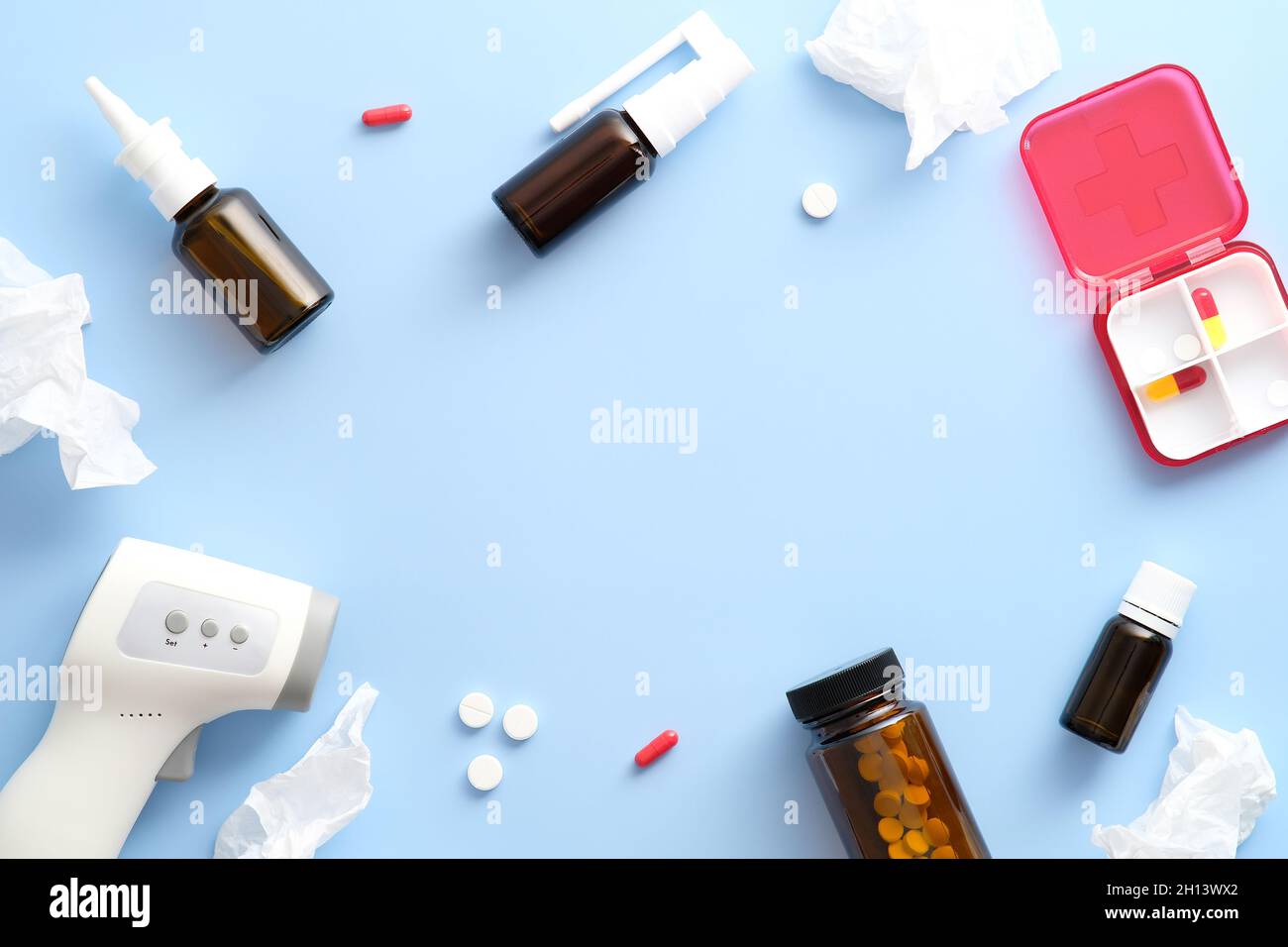 Traitements de la grippe.Sprays nasaux, pilules pour traiter les rhumes, mouchoirs, thermomètre numérique sur fond bleu pastel.Flat lay, vue de dessus, espace de copie. Banque D'Images