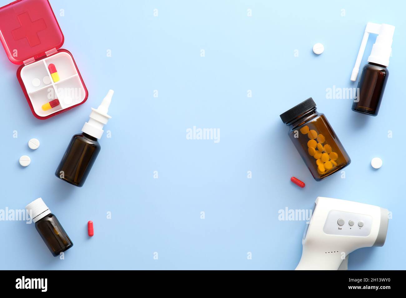 Trousse de premiers soins, vaporisateur nasal, pilules, thermomètre numérique sur fond bleu pastel.Flat lay, vue de dessus, espace de copie. Banque D'Images