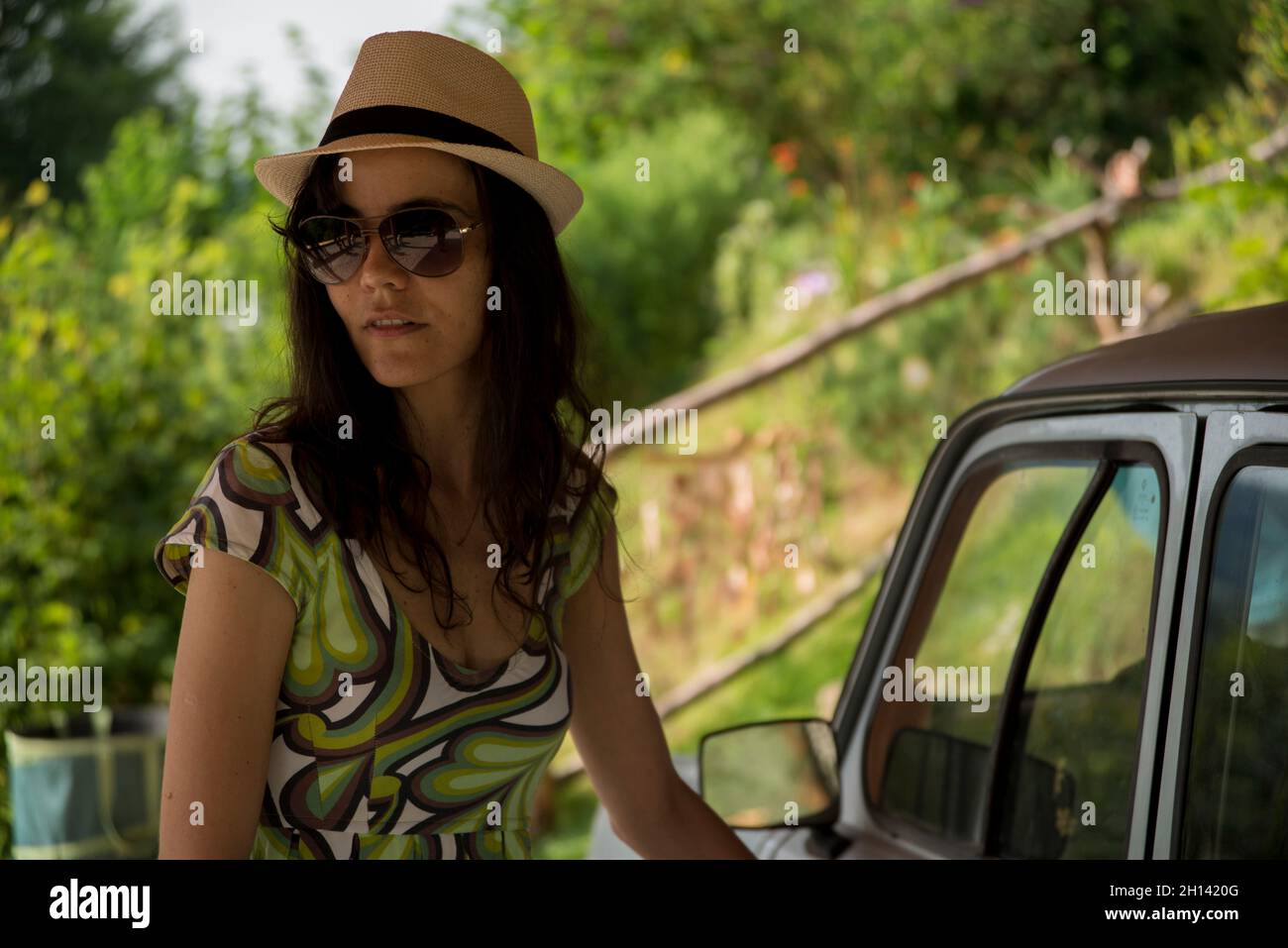 Femme avec chapeau, lunettes de soleil.Elle entre dans la vieille voiture Banque D'Images