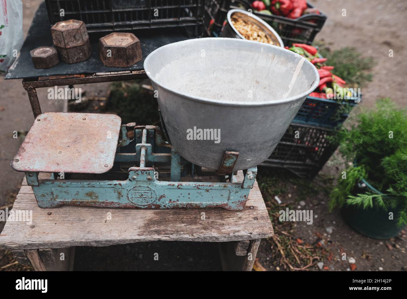 Image de faible profondeur de champ (foyer sélectif) avec de vieux poids à l'échelle sur la table d'un paysan roumain vendant des légumes de son jardin dans une zone rurale Banque D'Images