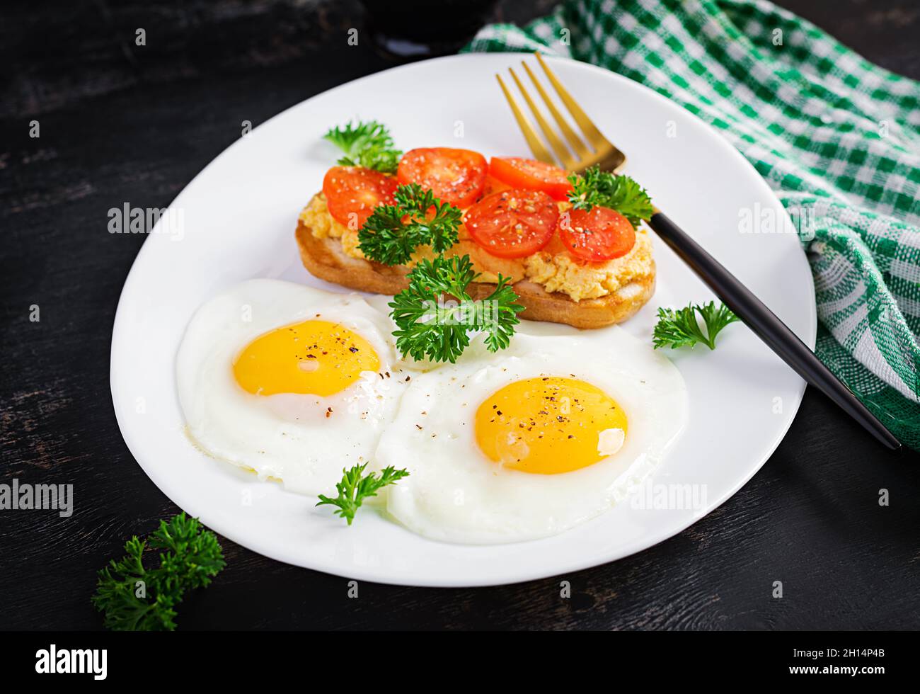 Des œufs frits et un sandwich au pâté de poulet grillé sur fond sombre. Banque D'Images
